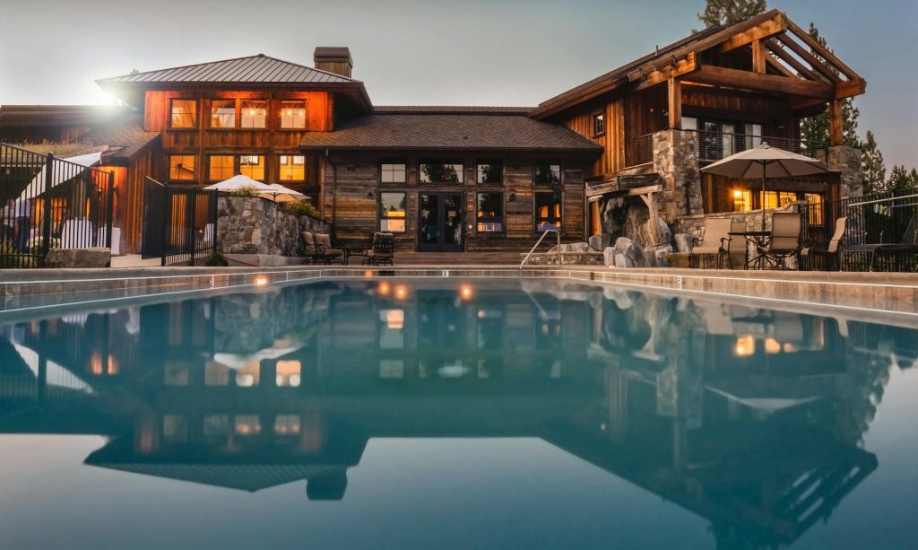 Stunning wooden villa with a large pool and cozy lights, perfect for a luxurious escape.
