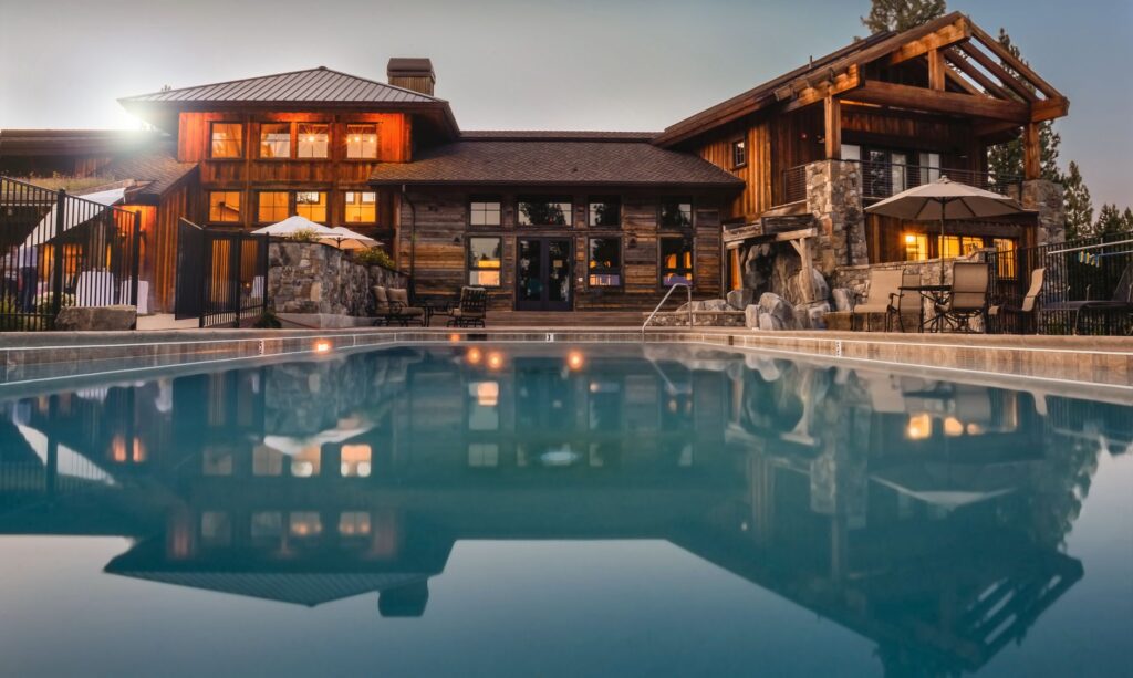 Stunning wooden villa with a large pool and cozy lights, perfect for a luxurious escape.