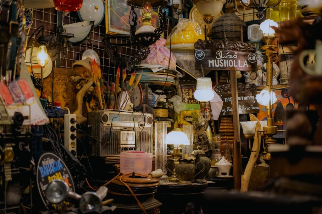 Interior of a cluttered antique shop filled with vintage items and a 'MUSHOLLA' sign.