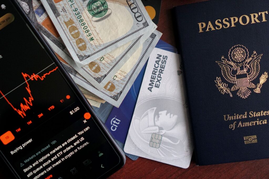 Stock trading concepts with passport, credit cards, cash, and smartphone app image.