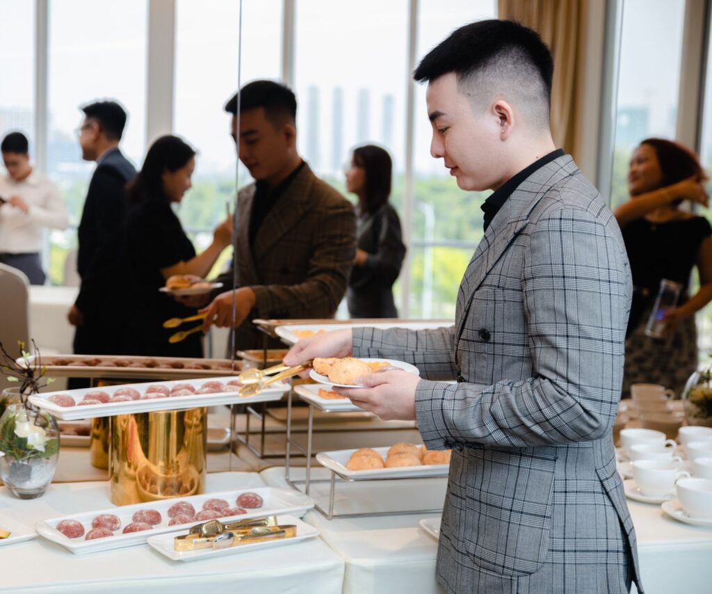 Businesspeople enjoying a buffet at a corporate event with diverse food options.