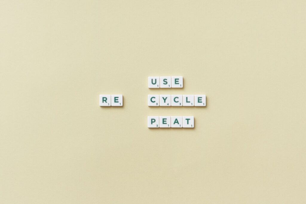 Letter tiles spelling 'reuse recycle repeat' on a simple background, promoting sustainability.