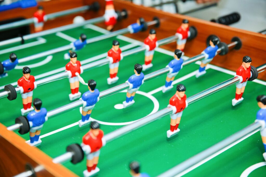 Vibrant foosball table game in play, showcasing red and blue teams in strategic setup.