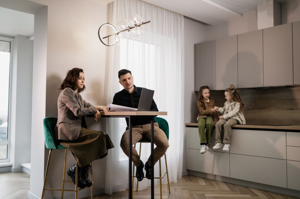 A modern family sitting together at home, using a laptop in a stylish kitchen setting.