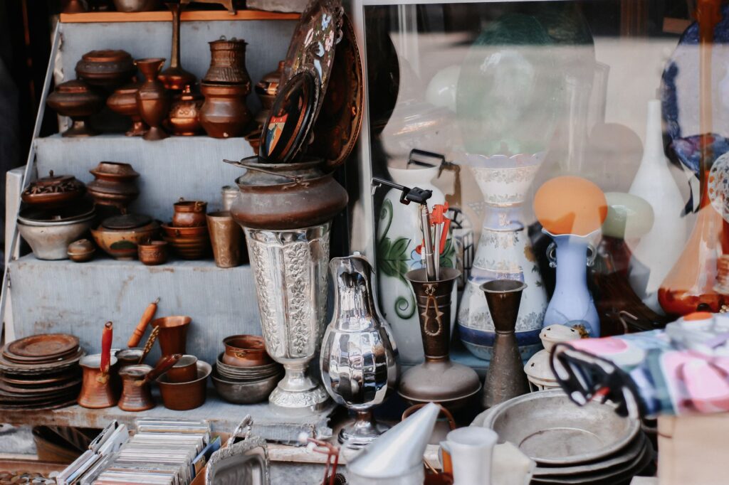 A diverse assortment of vintage ceramics, pots, and vases displayed in an antique shop setting.