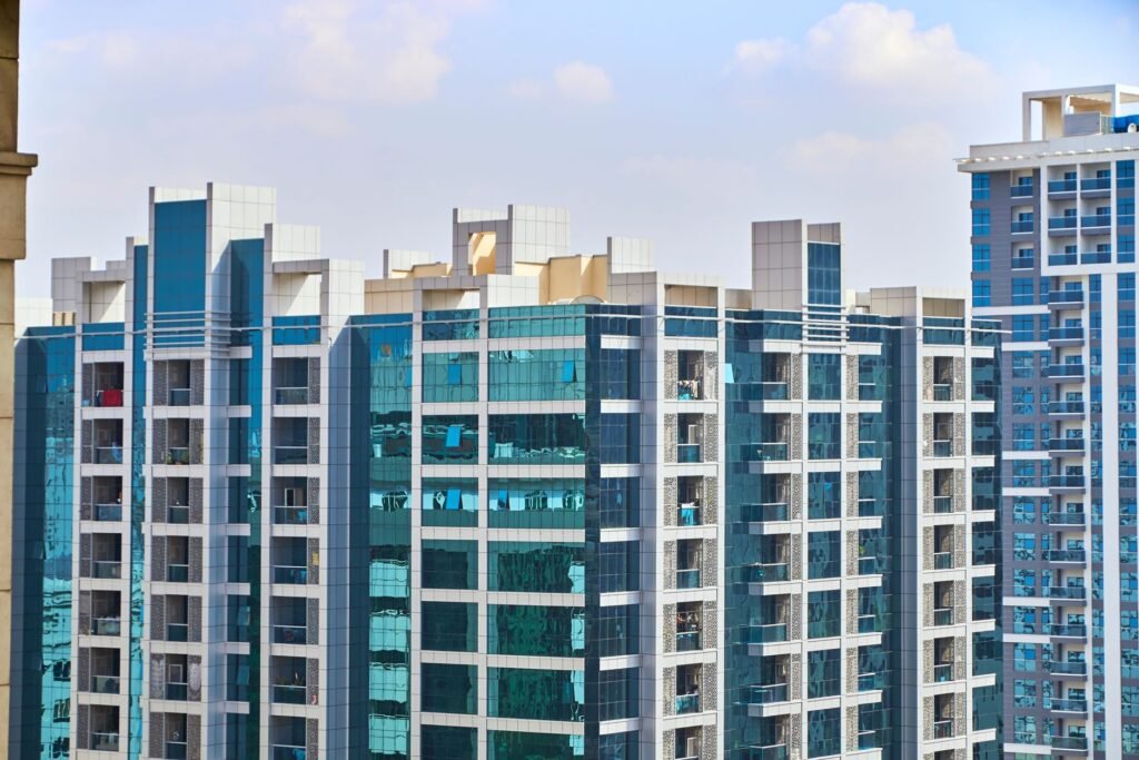 A cityscape view of modern high-rise buildings with reflective glass facades under a blue sky.