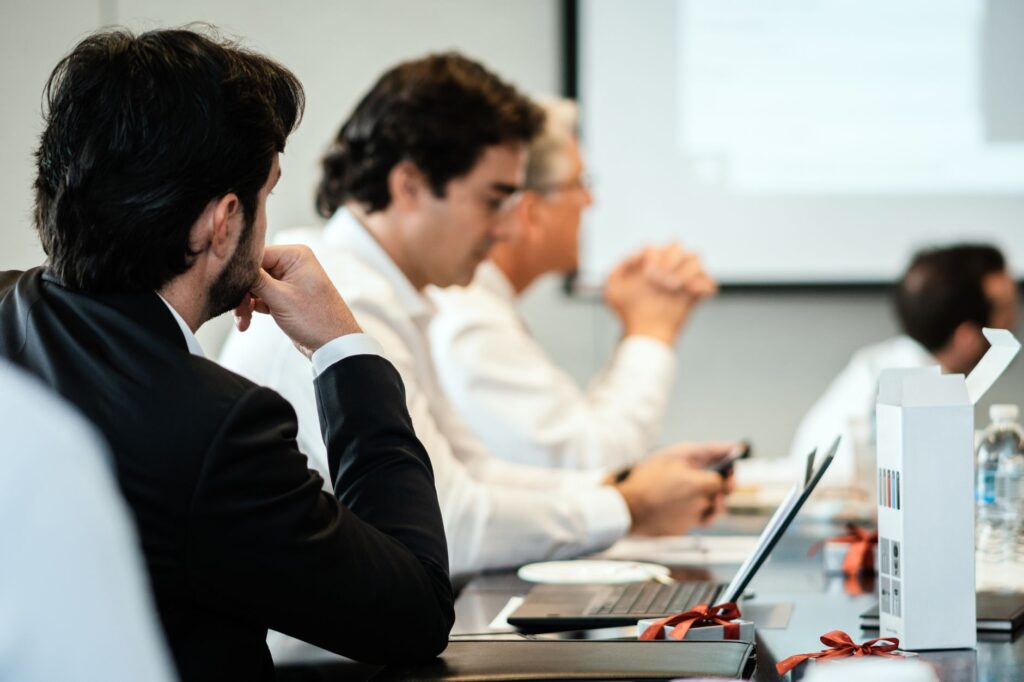 Corporate professionals in a formal meeting environment, focused on teamwork and collaboration.