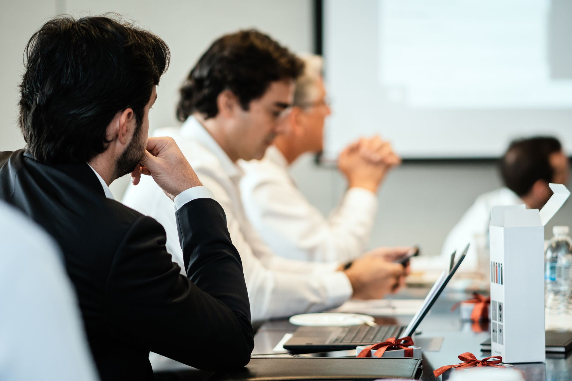 Corporate professionals in a formal meeting environment, focused on teamwork and collaboration.