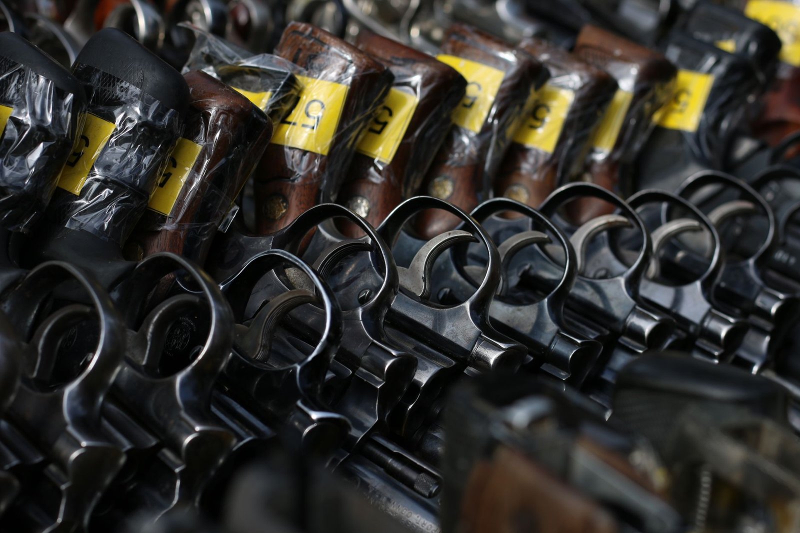 Close-up image of revolvers with yellow tags arranged on a rack.