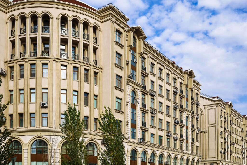 A classic urban residential building with rounded corners and detailed facades under a clear blue sky.