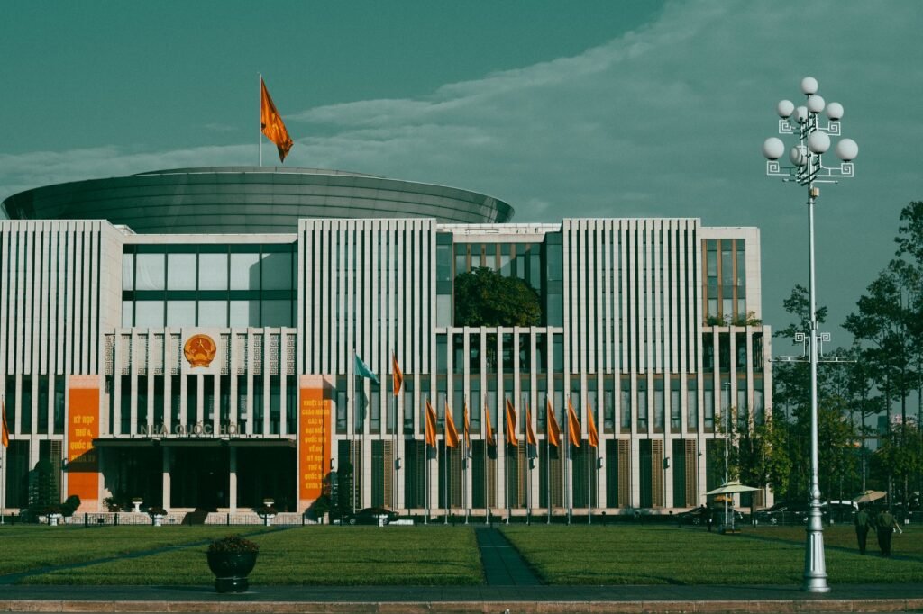 Front view of the National Assembly building in Hanoi, showcasing its modern architecture and national flags.