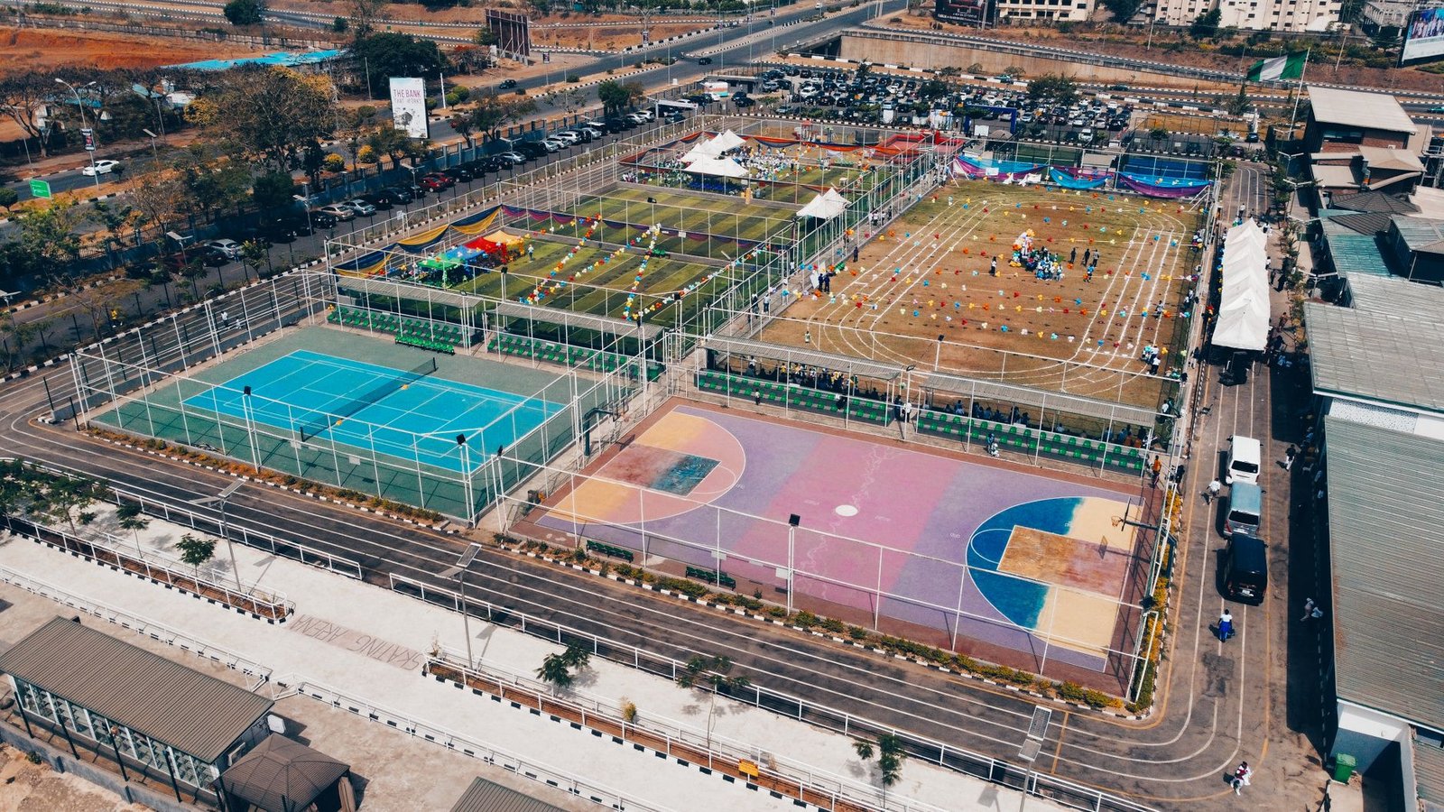 Aerial shot of colorful sports complex with tennis, basketball courts, and running tracks.