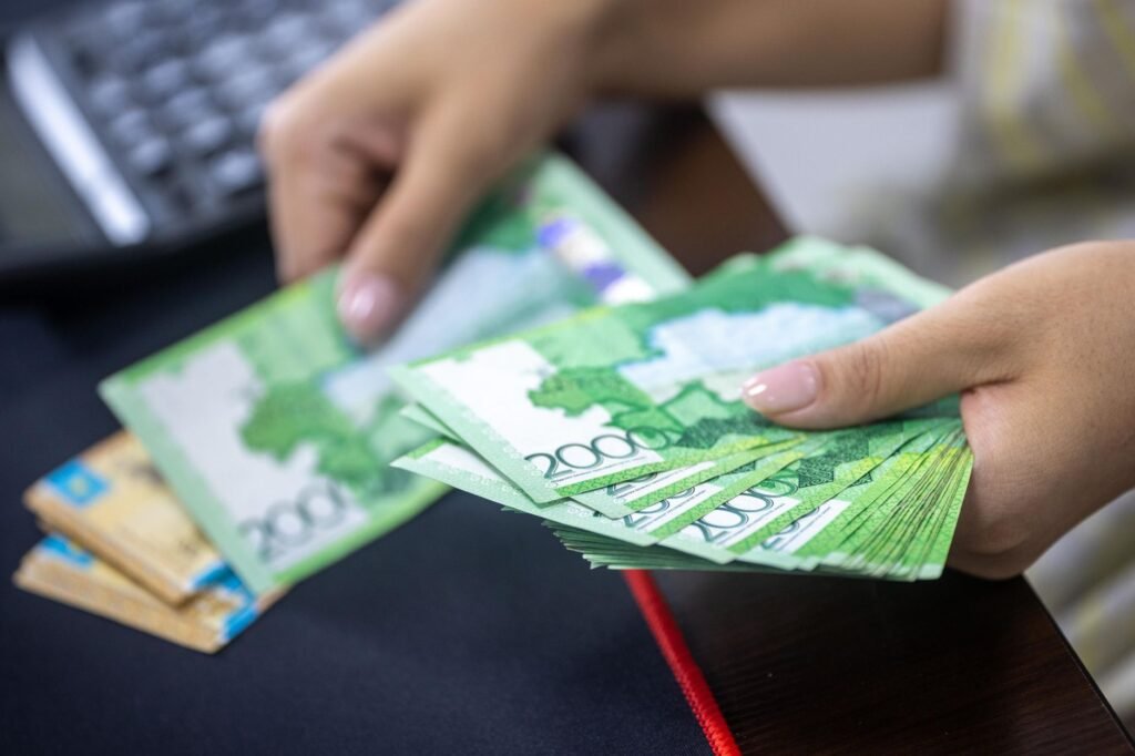 Person counting stacks of Uzbekistani som banknotes, showcasing financial transactions.