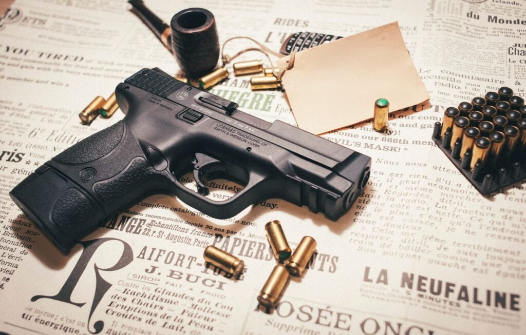A detailed view of a handgun with ammunition on vintage newspaper, highlighting firearm components.