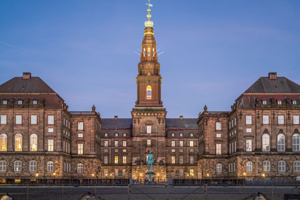 Stunning evening view of Christiansborg Palace with its illuminated spire in Copenhagen, Denmark.