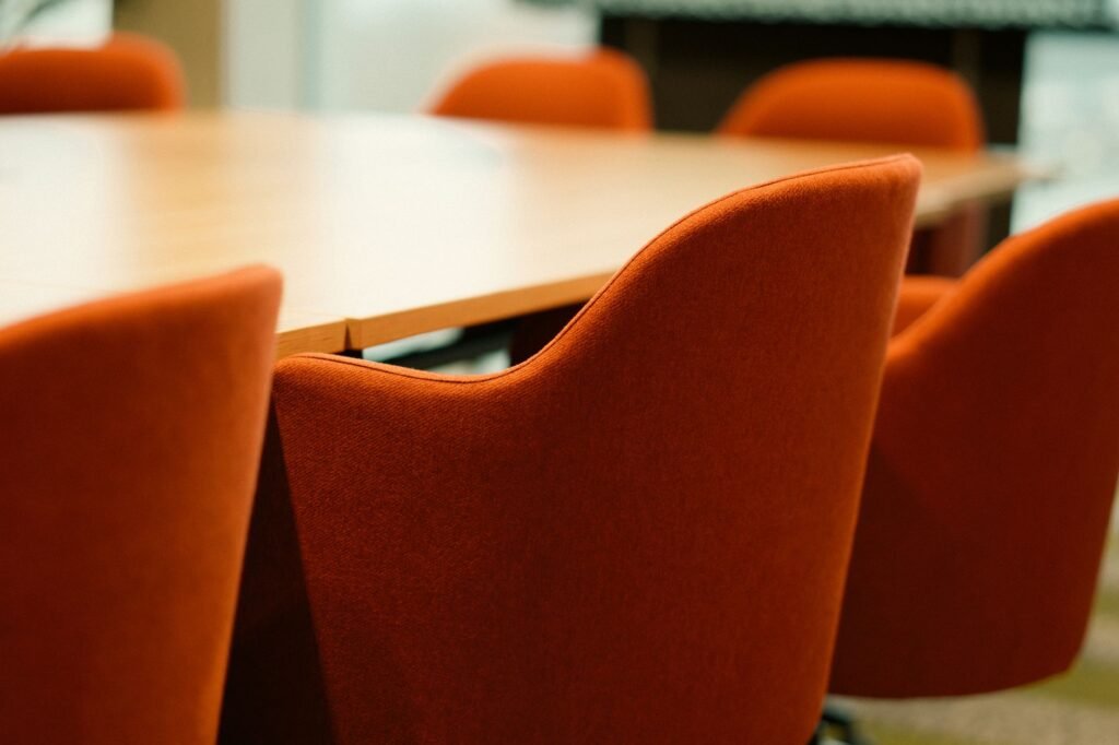 Close-up view of modern orange chairs around a conference table in an office setting.