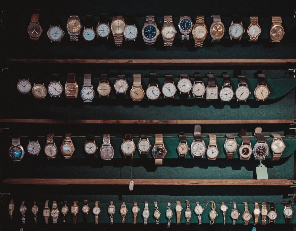 A diverse collection of vintage wristwatches lined on dark wooden shelves with ambient lighting.