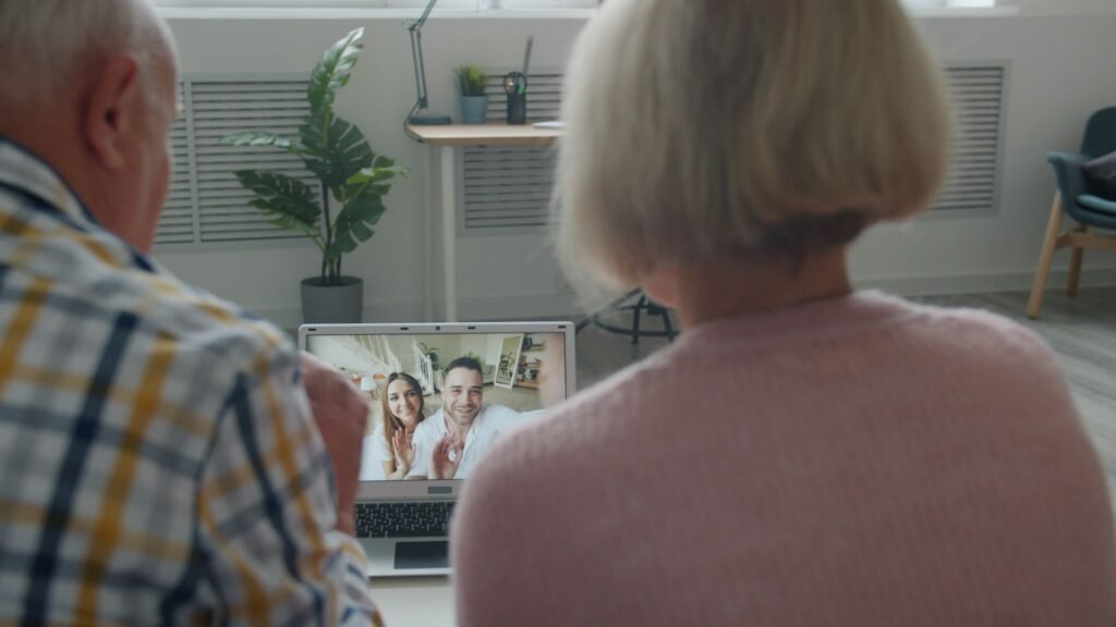 Elderly couple having a video call with family on a laptop at home.