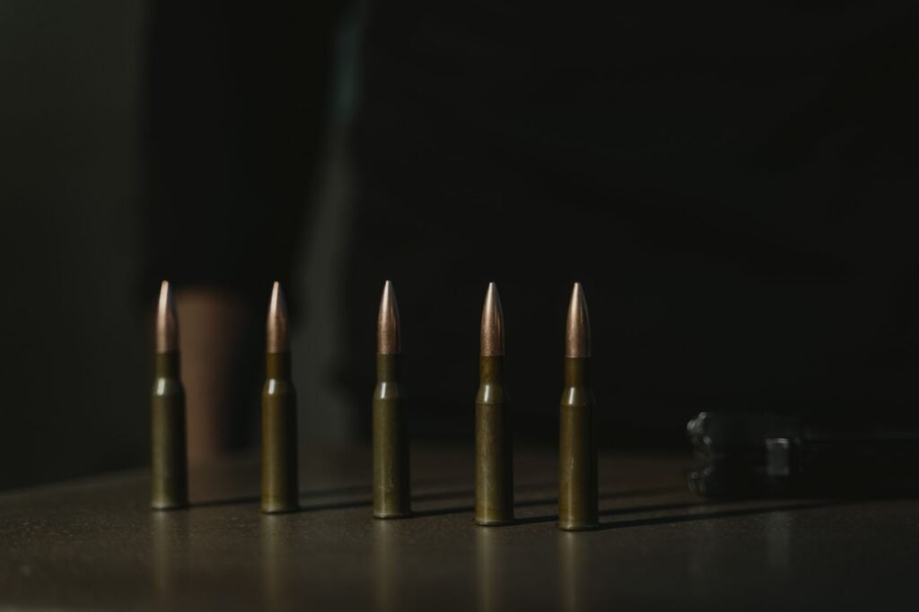 Close-up shot of a row of bullets on a dark surface, emphasizing their metallic texture.
