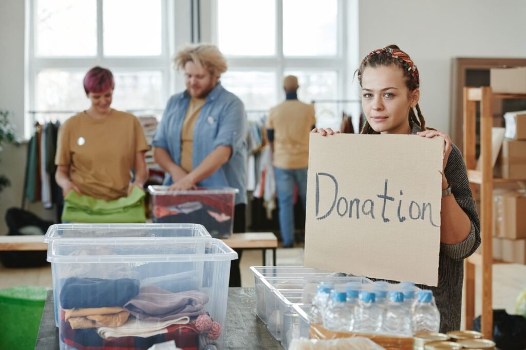 Group of volunteers organizing clothing and water donations indoors.