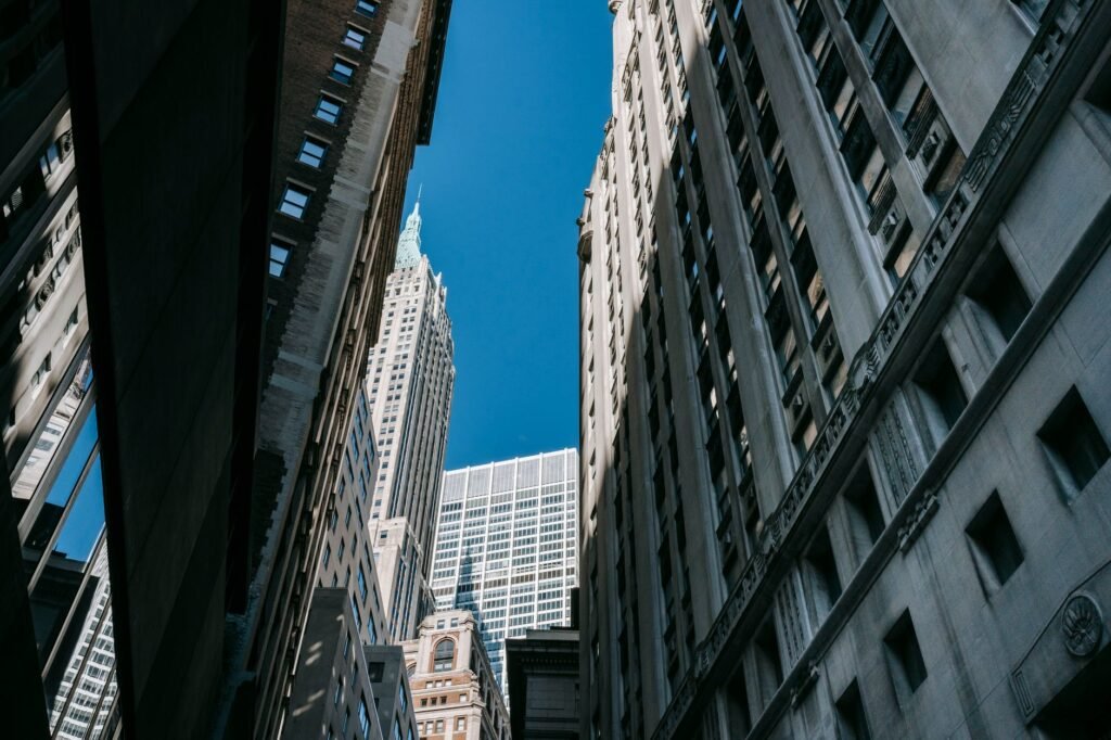 From below of tall multistory buildings and office towers located in business district under blue sky