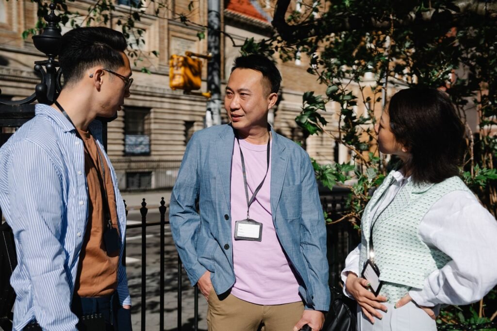 Three colleagues having a discussion in a sunny outdoor urban setting.