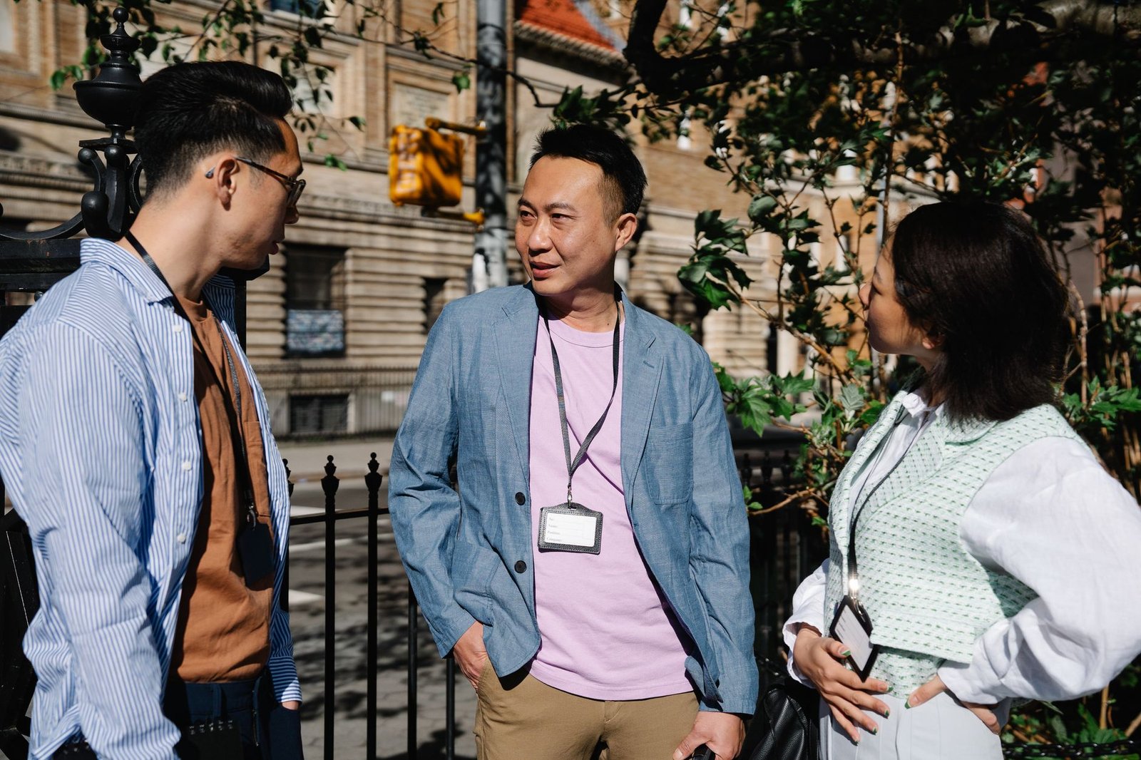 Three colleagues having a discussion in a sunny outdoor urban setting.