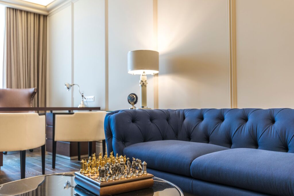 Stylish living room featuring a blue couch, chess set, lamps, and modern decor.