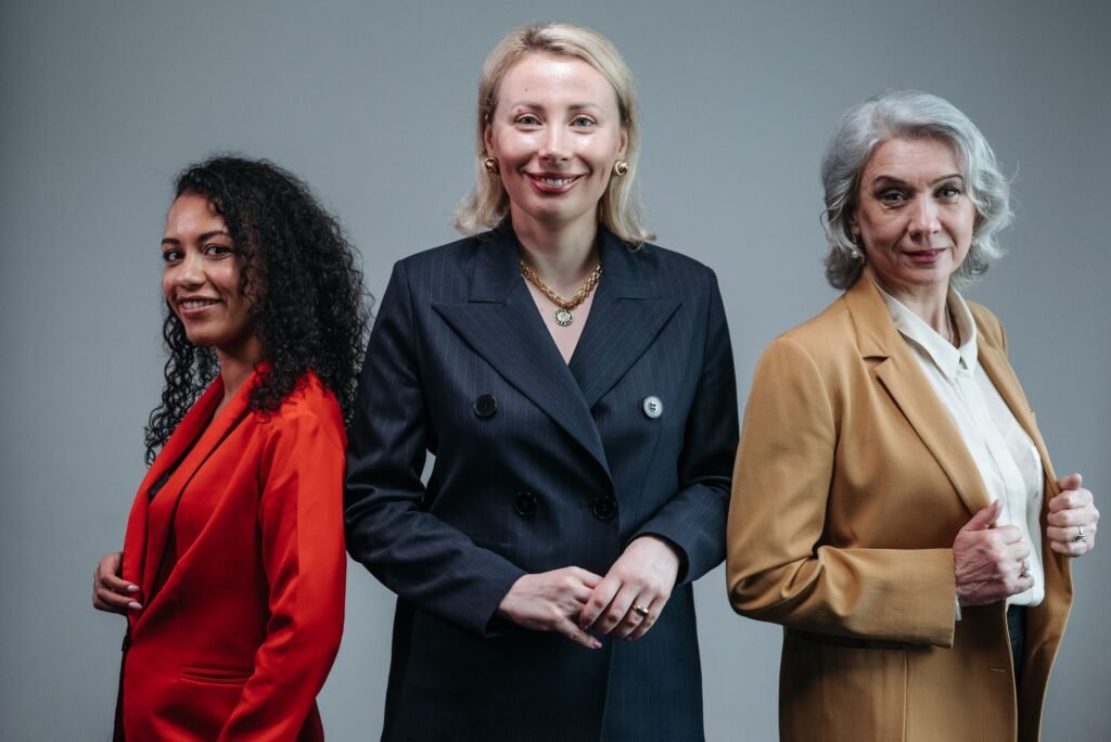 Three confident business women standing in fashionable attire, exuding professionalism.