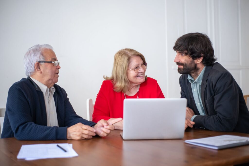 Elderly couple having a consultation with a professional advisor in a bright indoor setting.