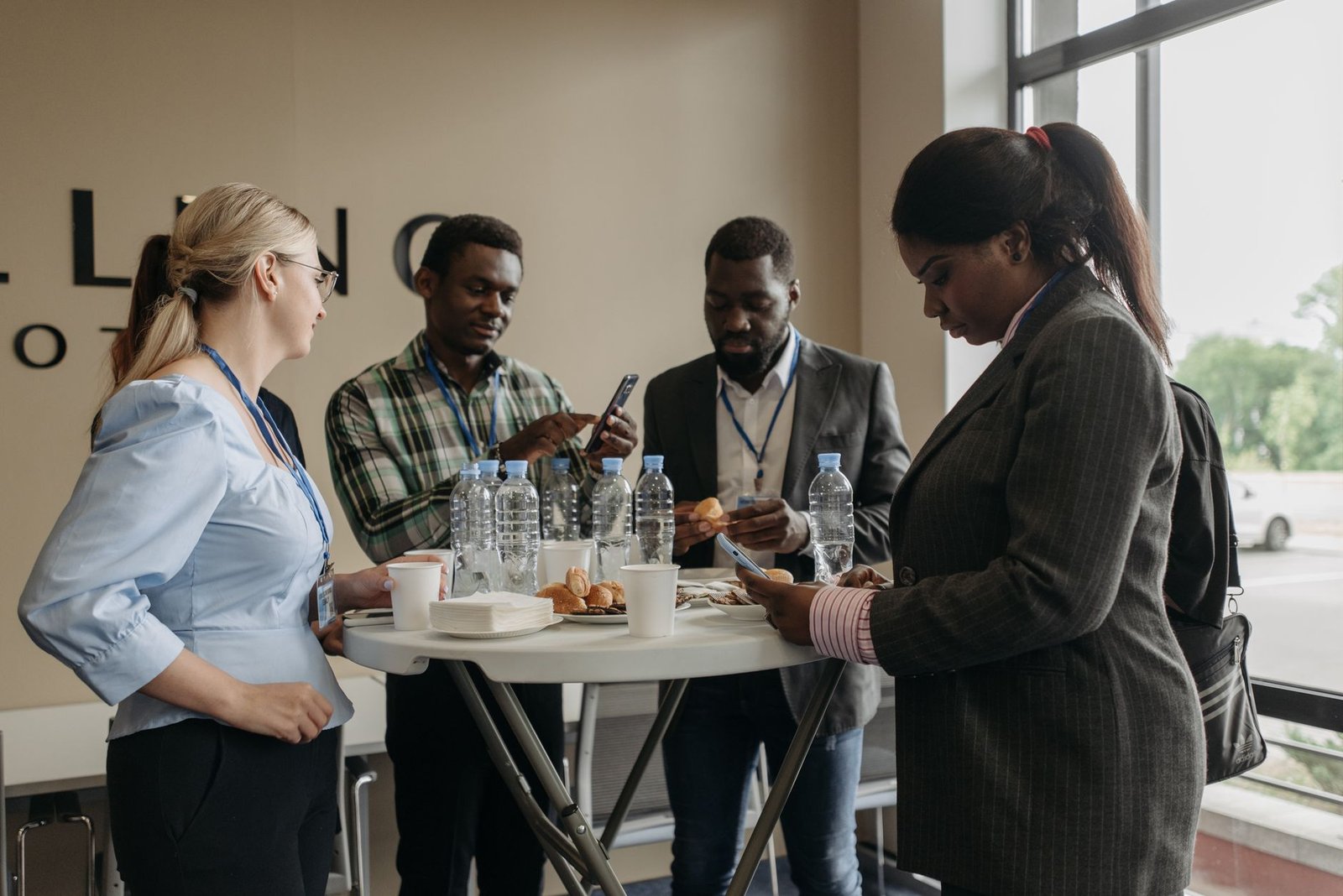 A group of diverse professionals networking and discussing business during a conference break indoors.