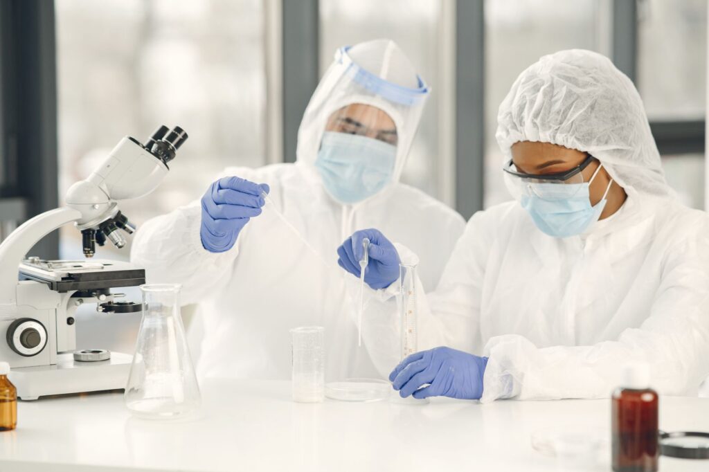 Two scientists in protective gear conduct research in a laboratory using scientific equipment.