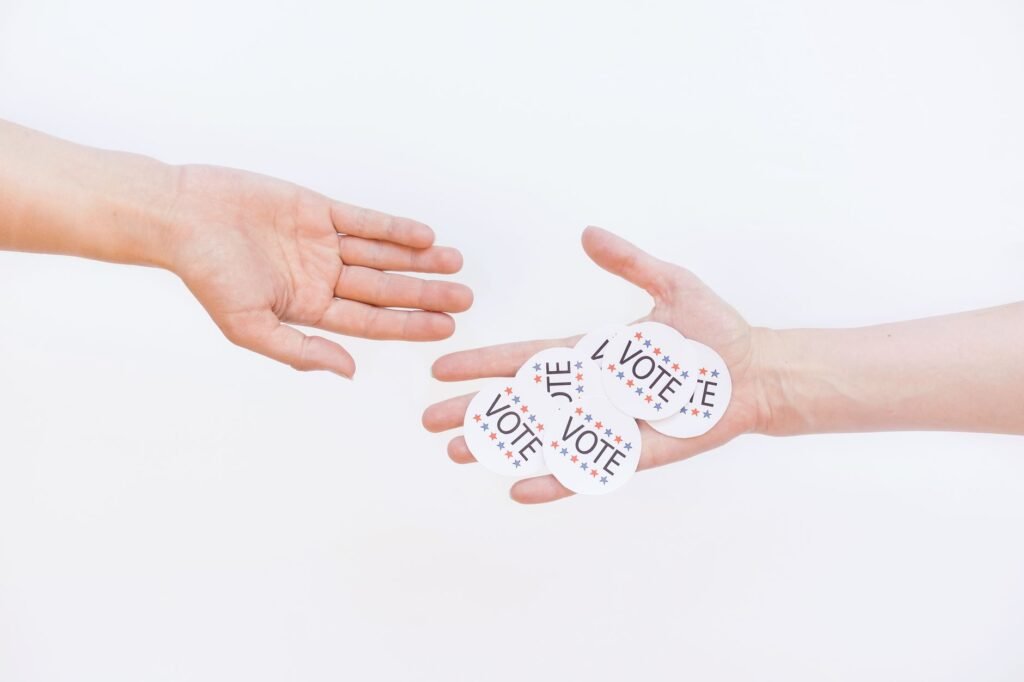 Close-up of hands exchanging vote stickers, symbolizing engagement in democratic election.