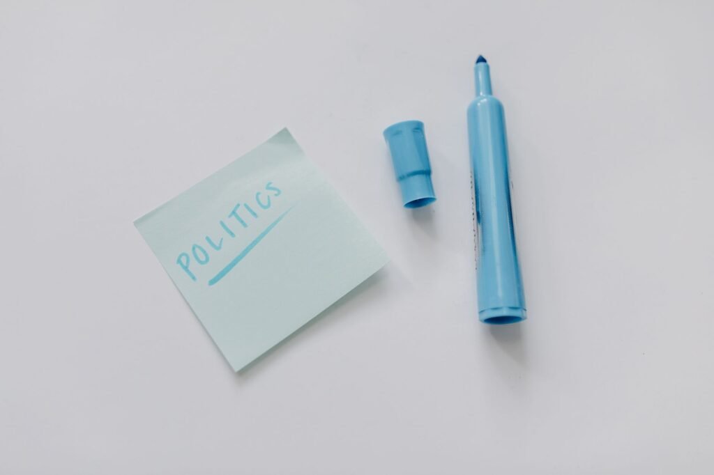 A blue marker and a note reading 'politics' on a white surface, top view.