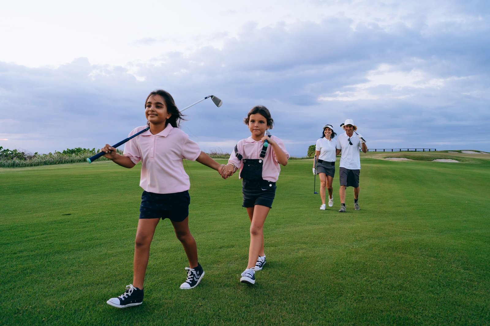 A family enjoys bonding outdoors on a lush golf course holding golf clubs.