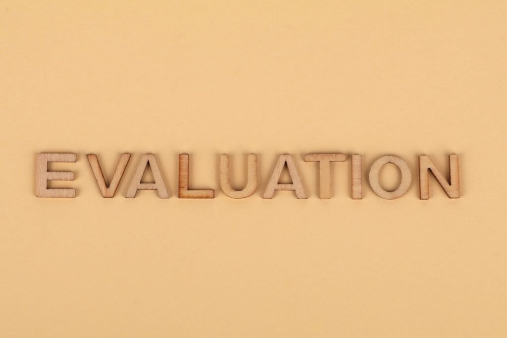 Wooden letter blocks arranged to spell 'evaluation' on a beige background.