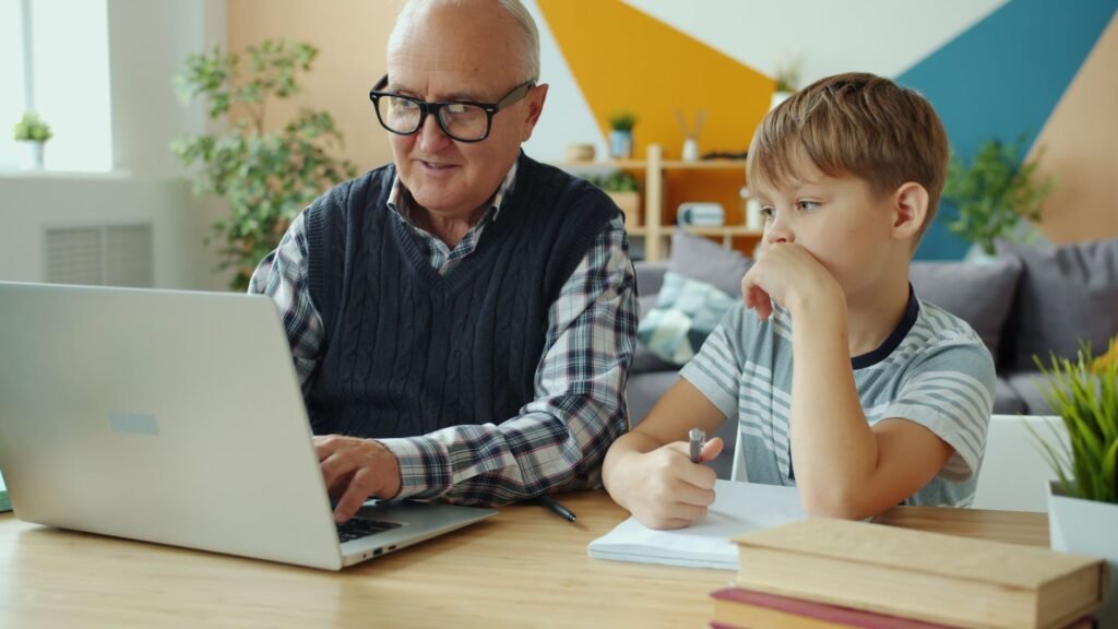Senior man and young boy using a laptop at home, focusing on learning and bonding.