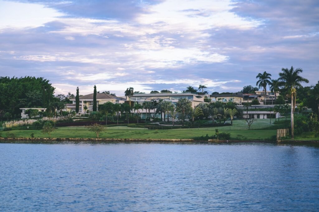 Scenic view of luxurious villas by the water surrounded by lush tropical gardens and serene skies.