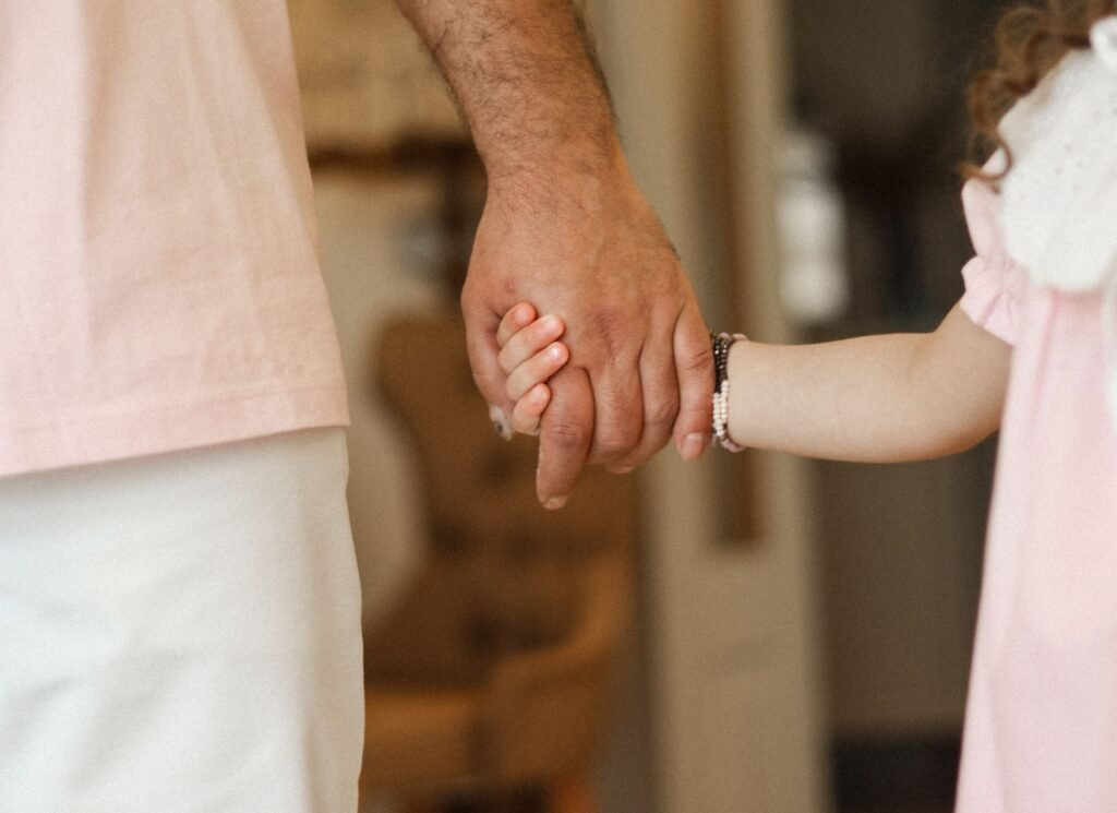 A touching image of a father holding his daughter's hand, displaying warmth and affection.