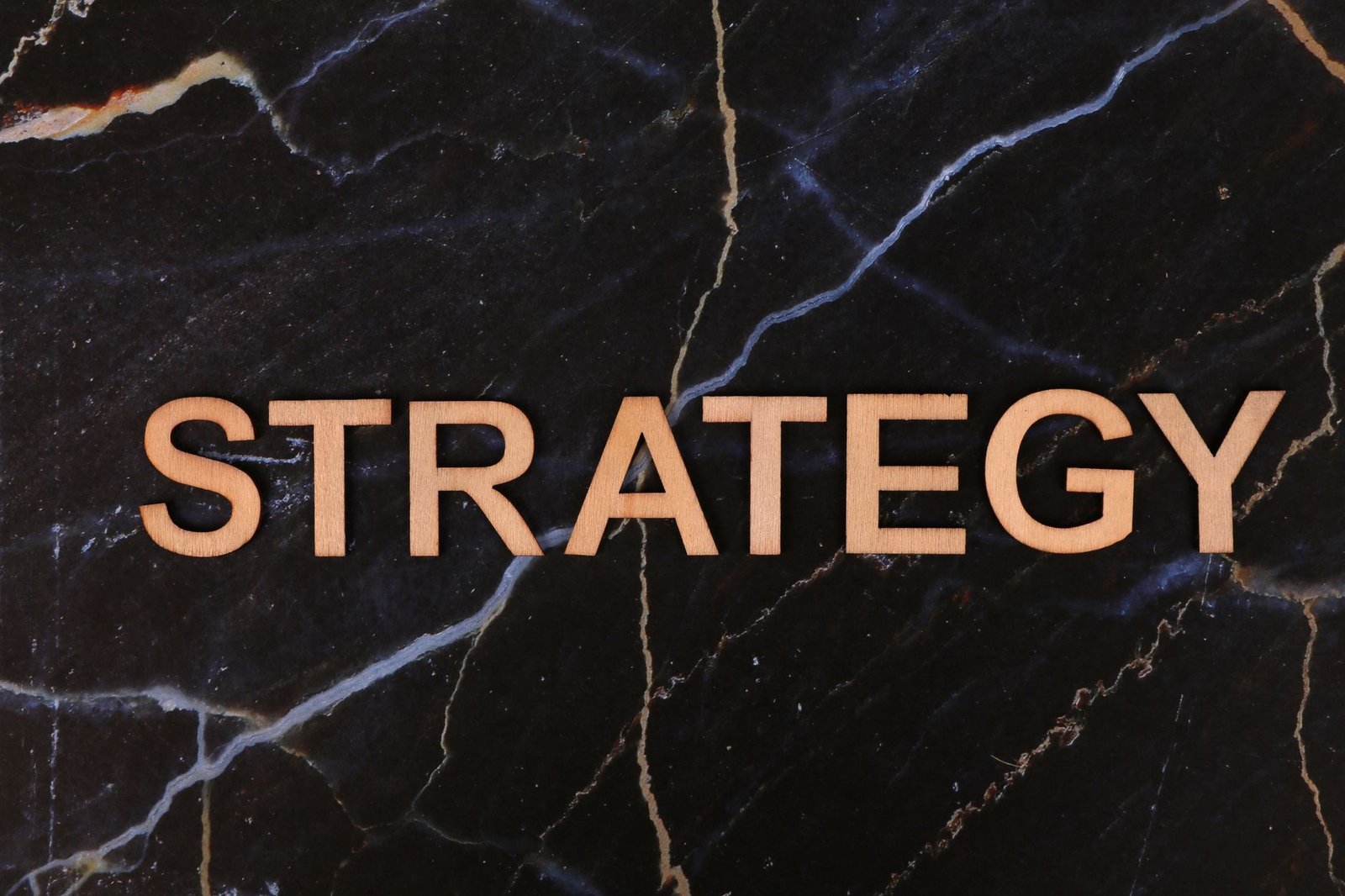 Strategic planning concept with 'Strategy' in wooden letters on dark marble.
