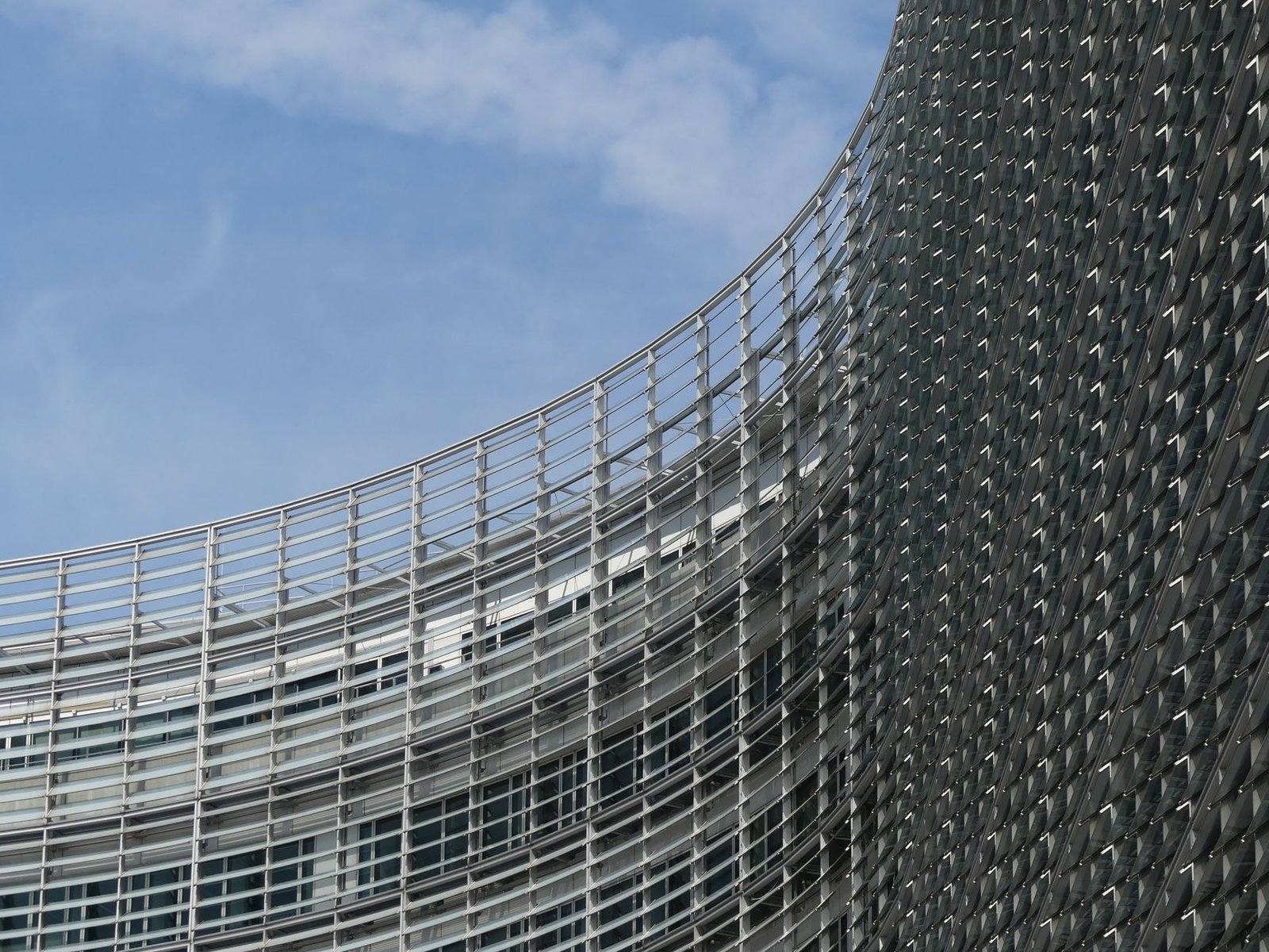 Curved facade of the European Commission building in Brussels under a clear sky.