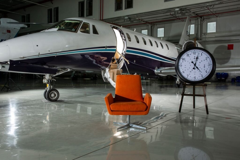 A private jet and modern furnishings inside an illuminated airport hangar.