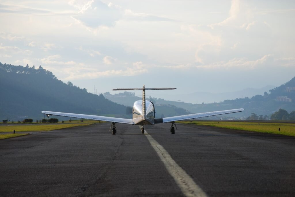 Private aircraft on runway preparing for takeoff with scenic mountain view in the background.