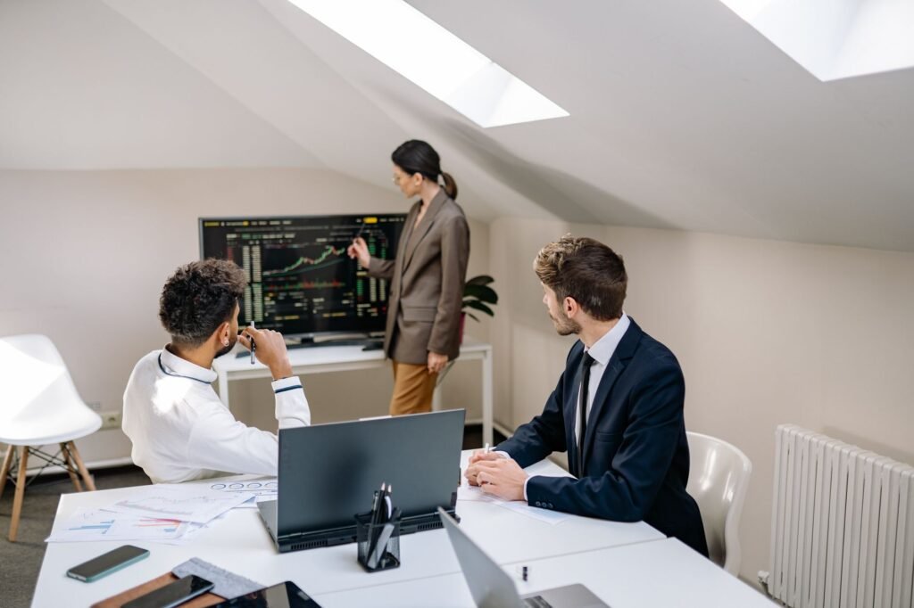 Professionals discussing stock market trends with charts in an office setting.