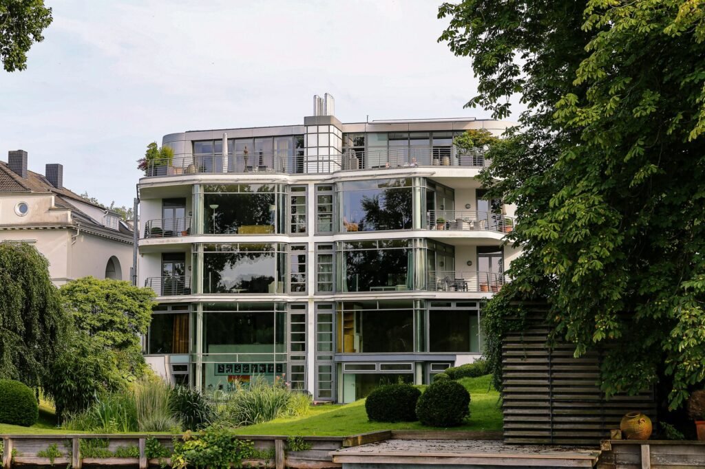 Contemporary glass facade building in Hamburg, surrounded by lush greenery.